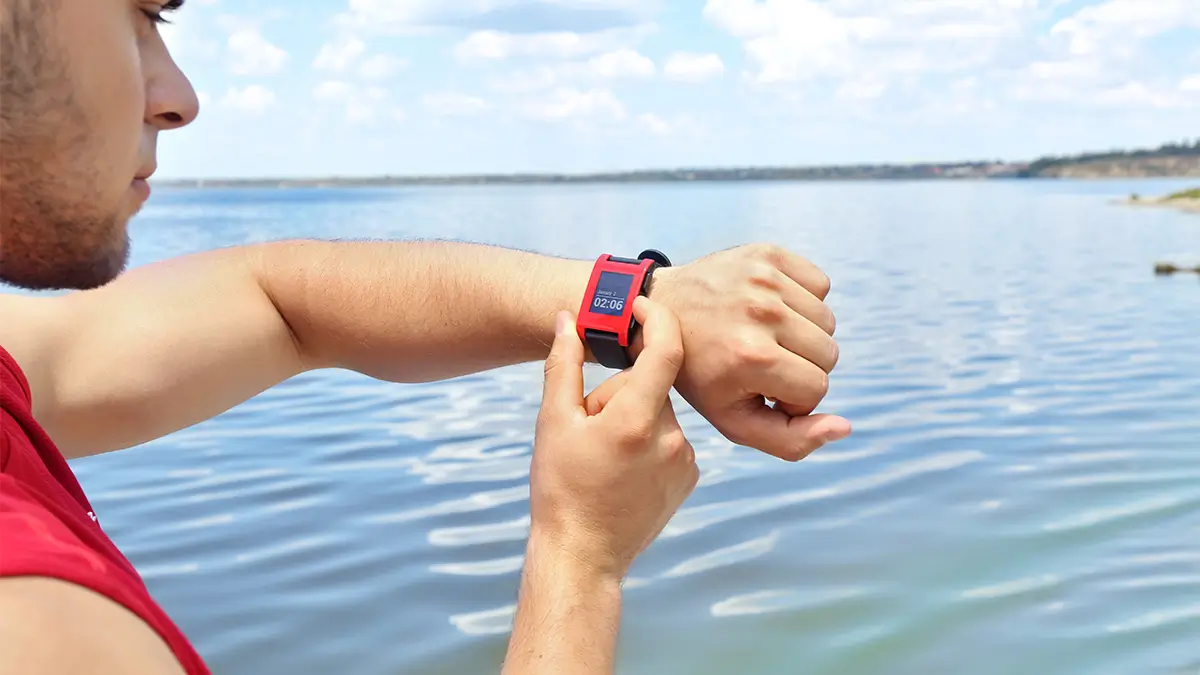 women wearing waterproof fitness tracker in hand, standing in swimming pool